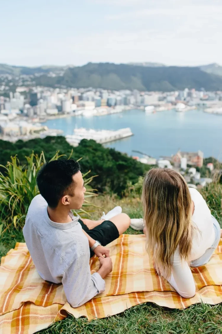 young couple lying on picnic blanket overlooking wellington city at mt victoria lookout 2