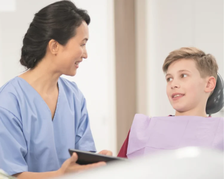 Oral Health Therapist educating a young patient about dental hygiene (stock image)