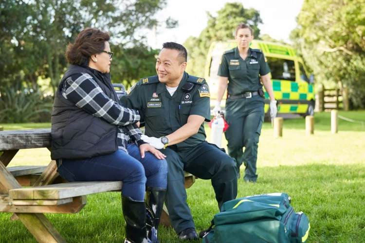 A St. John Paramedic properly doing a routine checkup on a patient in the park