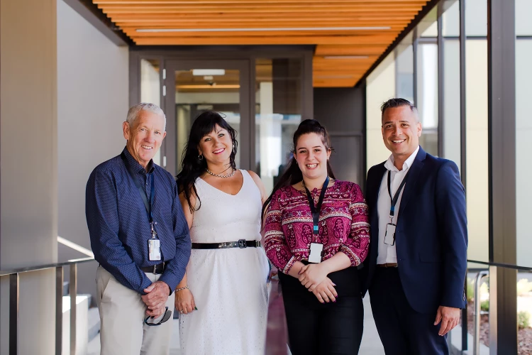 Team of four corporate staff posing in a hallway