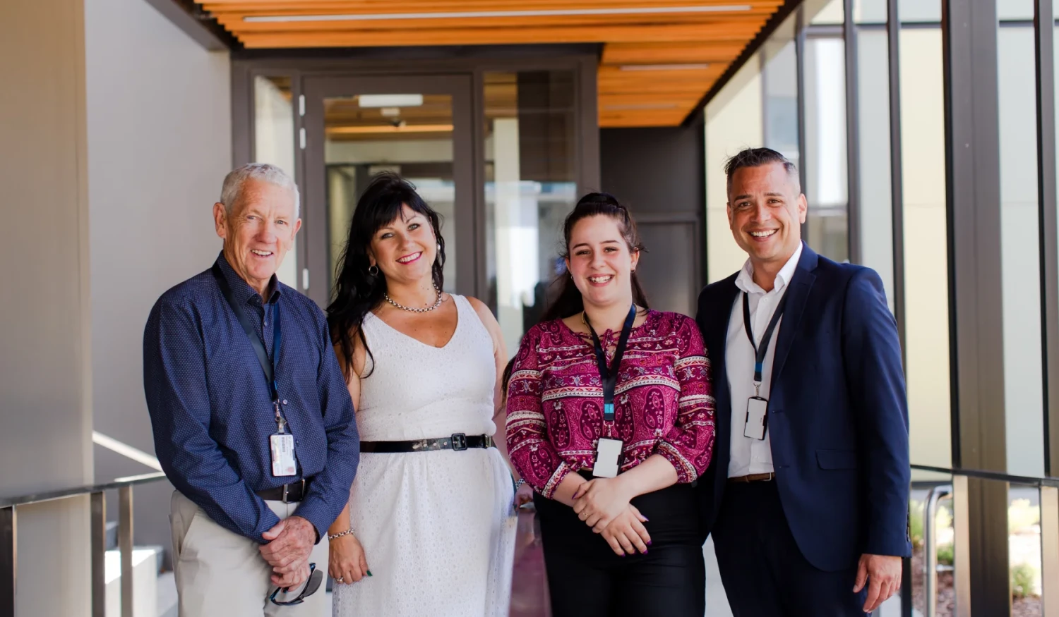 Four Health New Zealand Corporate leaders standing by the building entranceway side by side.