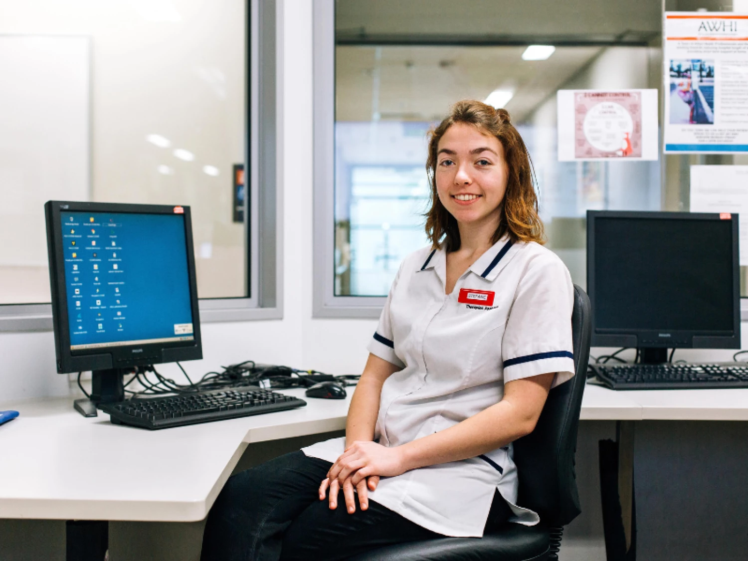 Health New Zealand Kaimahi Stefanie sitting at her desk smiling in her white uniform