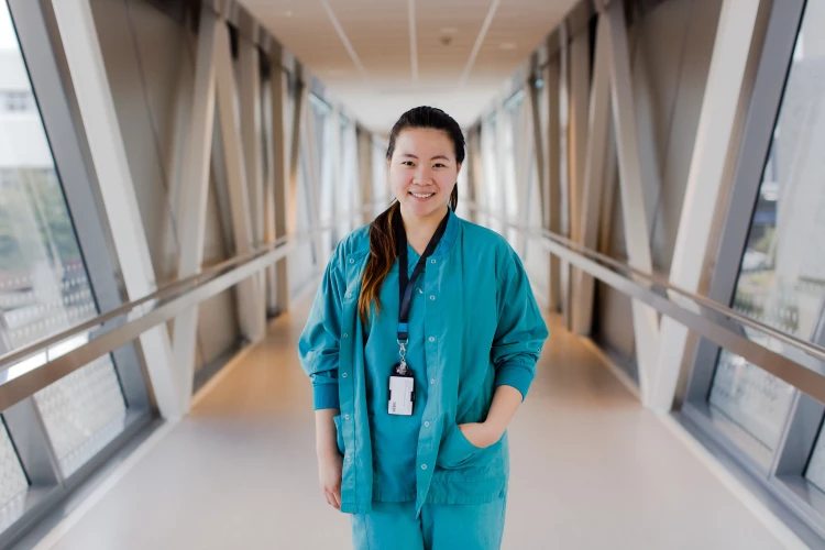 A Health New Zealand nurse standing relaxed smiling in the hallway