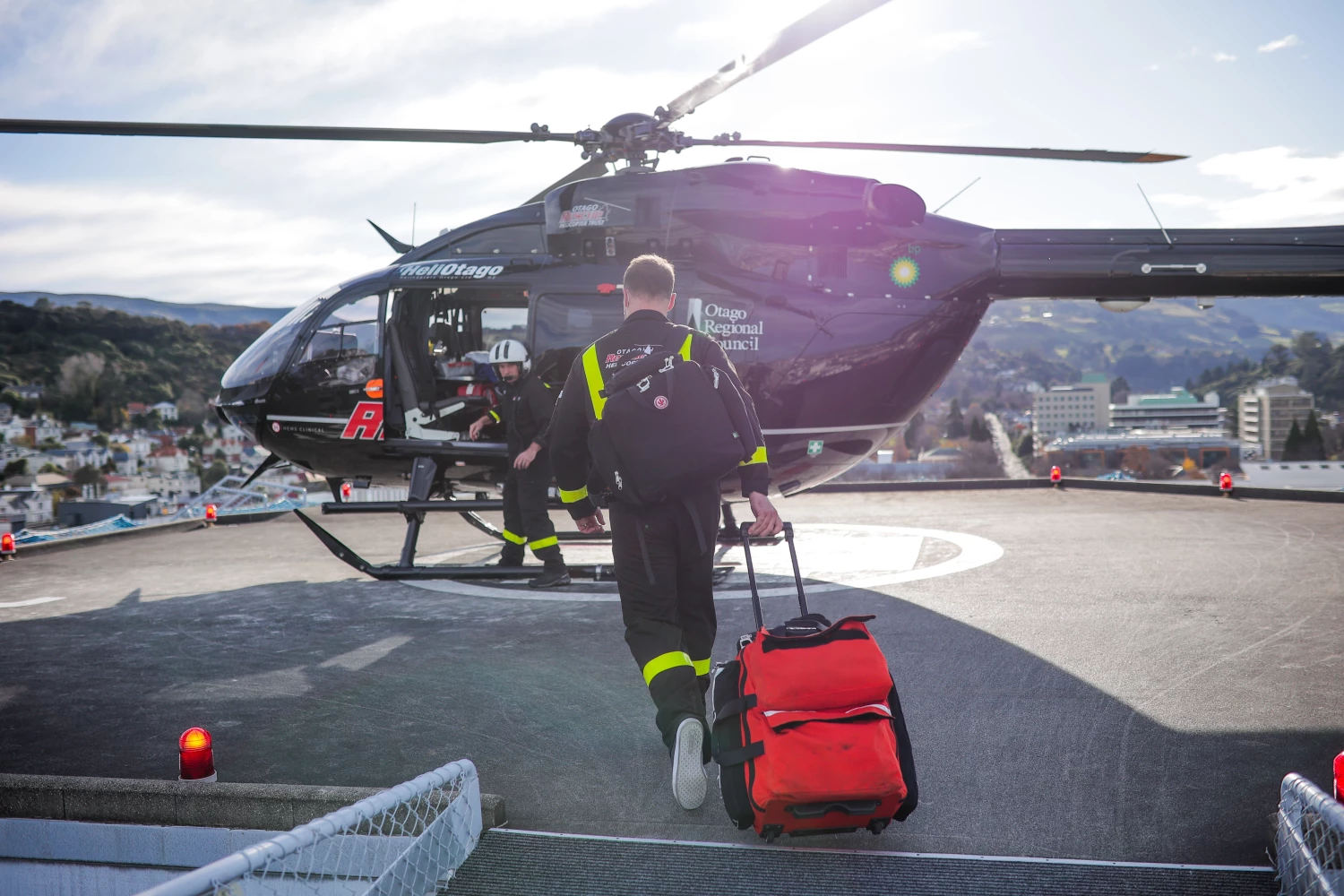 A Critical Care Specialist walking towards a rescue helicoopter on a hospital helipad