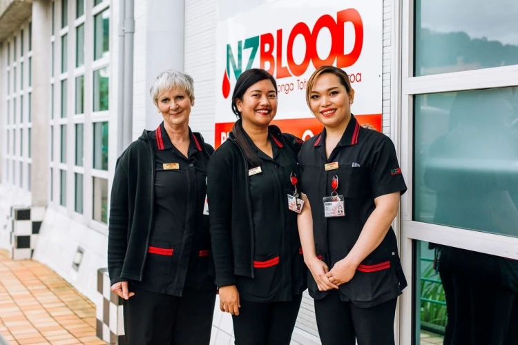 Three nurses in uniform standing outside the NZ Blood Service building