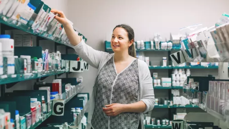 Hospital pharmacist Rosanna reaching up for some medicines in the top shelf in the hospital pharmacy.