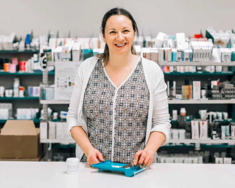 Hospital pharmacist Rosanna standing at the hospital pharmacy counter with presciption meds she has prepared earlier.