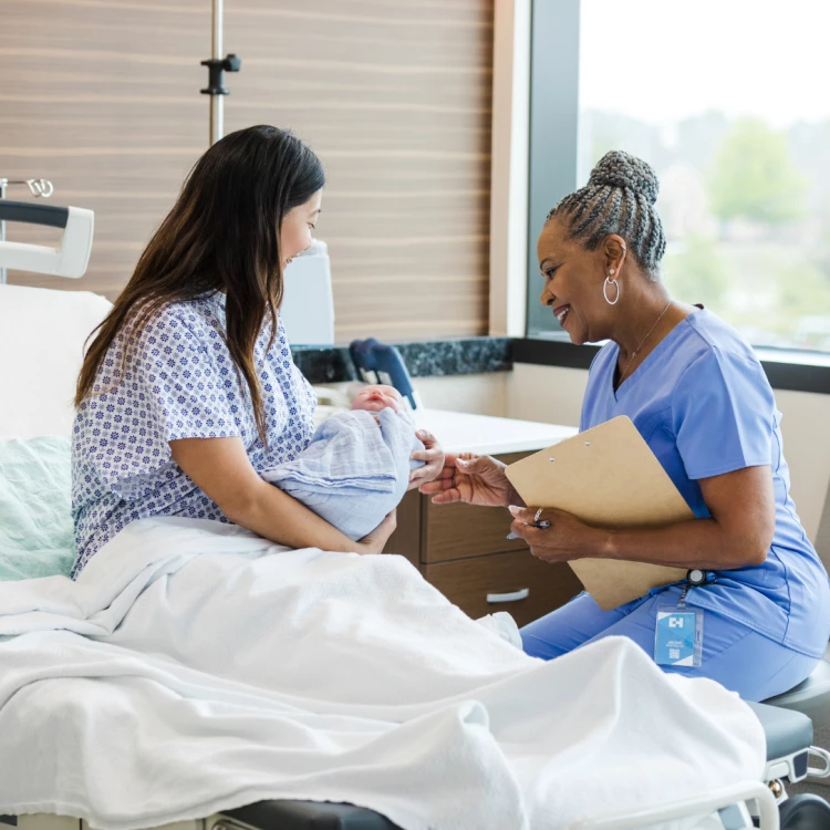 Senior midwife with new mum (stock image)