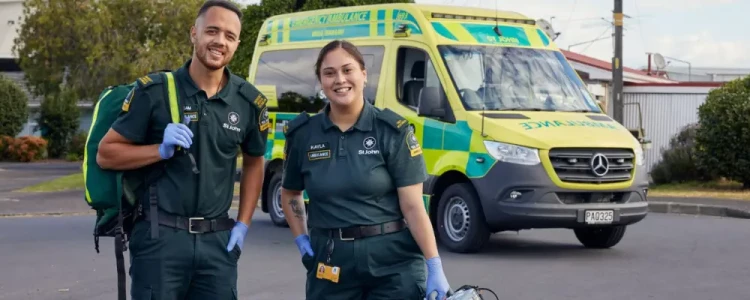 Two St. John paramedics standing in the parking lot in front of a St. Johns ambulance.