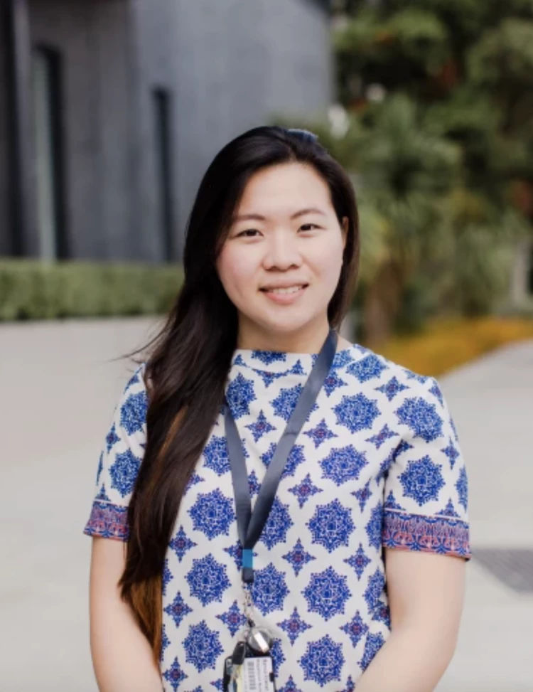 Manica, a Health New Zealand healthcare professional standing outside a hospital building. 